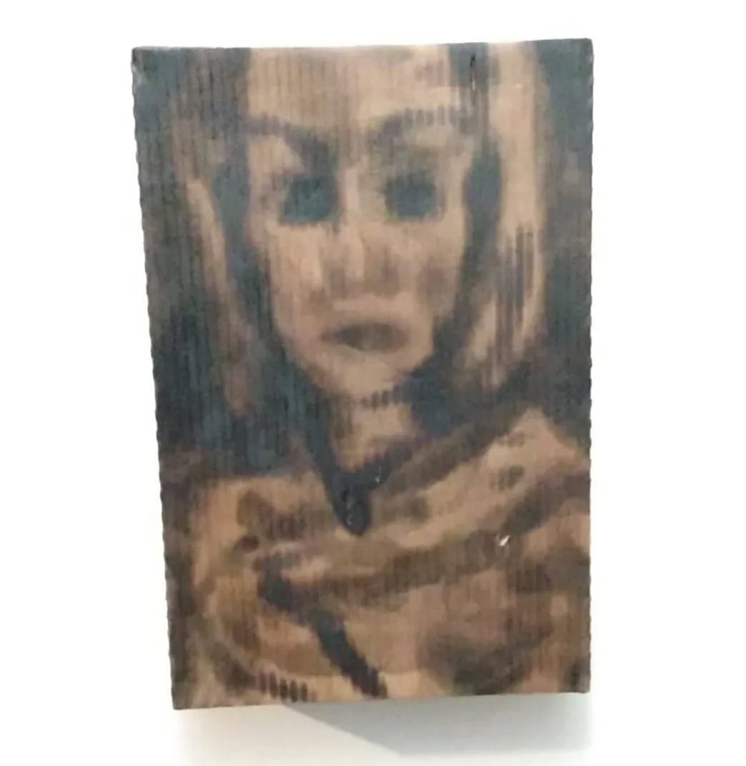 Scorched face burned into cardboard