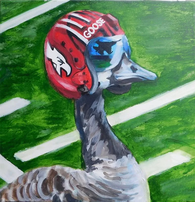 Goose wearing a red football helmet on a football field