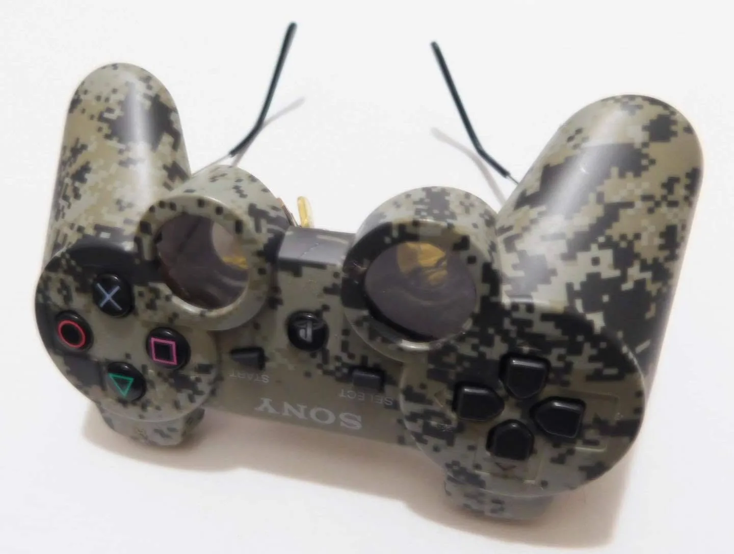 Angled white-background photograph of camo PlayStation controller sunglasses