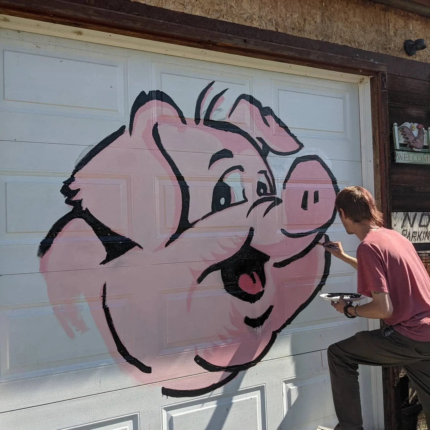 Black linework being added to the pink pig mural