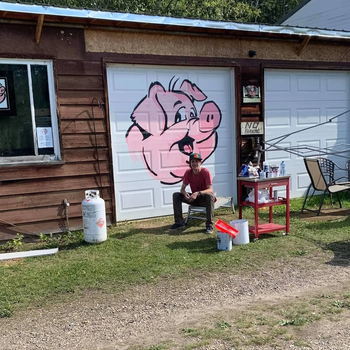 Representative image from the 2021 Hog Saloon mural project: Derek Boe seated before the finished mural